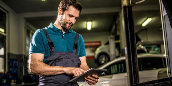 man in garage with car and tablet